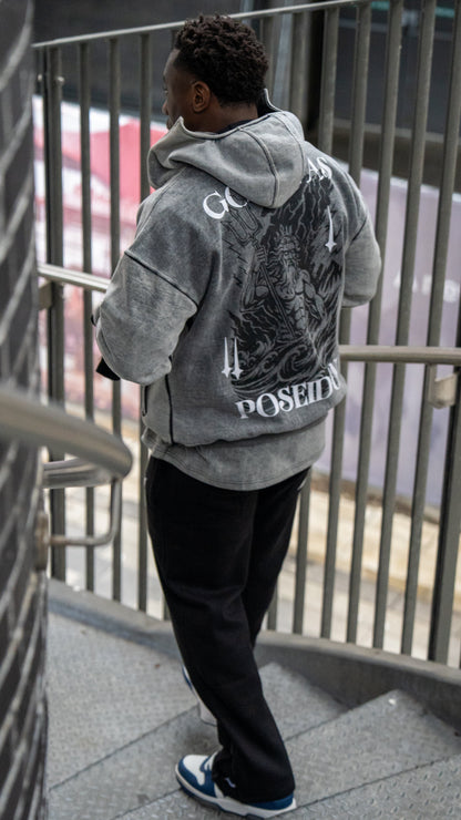 Person wearing a gray hoodie with a graphic design, standing on a staircase.